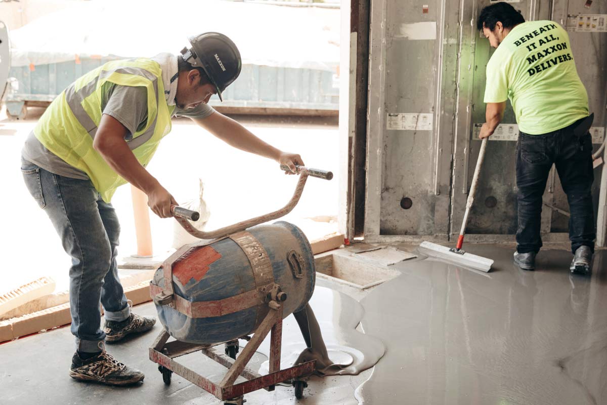 Installers pouring self-leveler to create a smooth, flat subfloor before vinyl plank goes down
