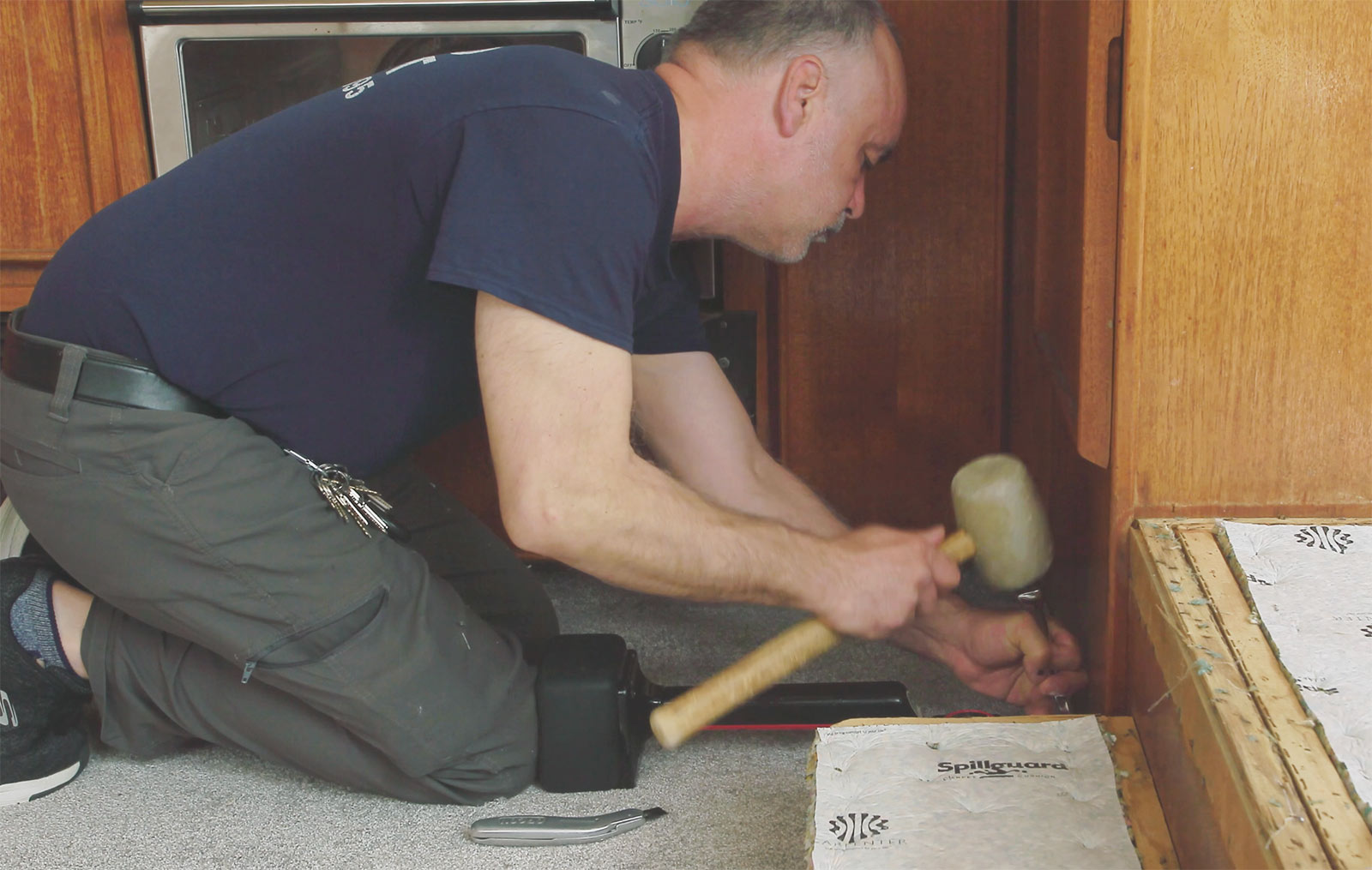 Carpet installer using rubber mallet to install carpet near the wall