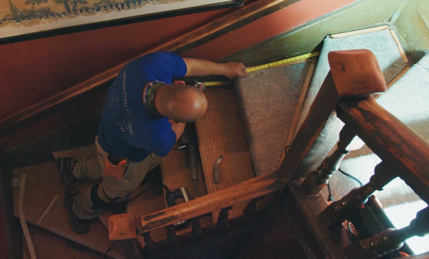 Installer measuring a stair tread before installing stair carpet