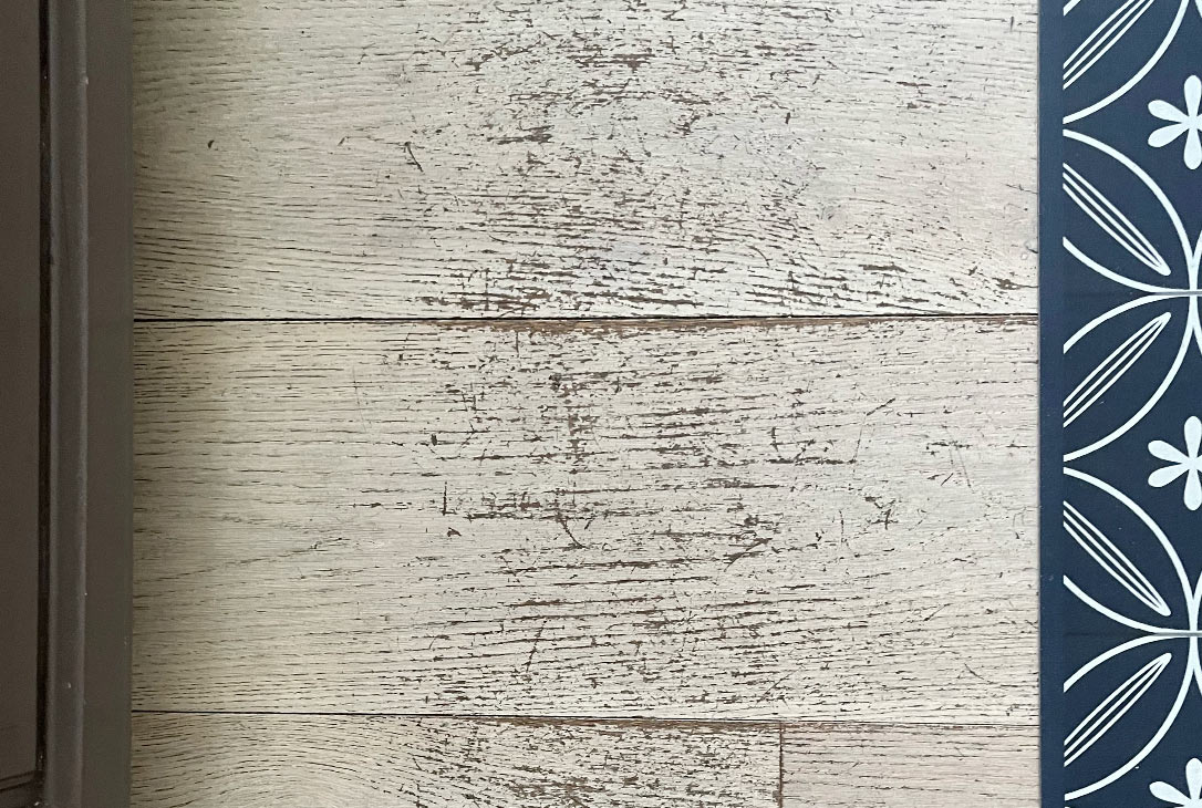 Scratched engineered hardwood floor in a kitchen near the island and sink