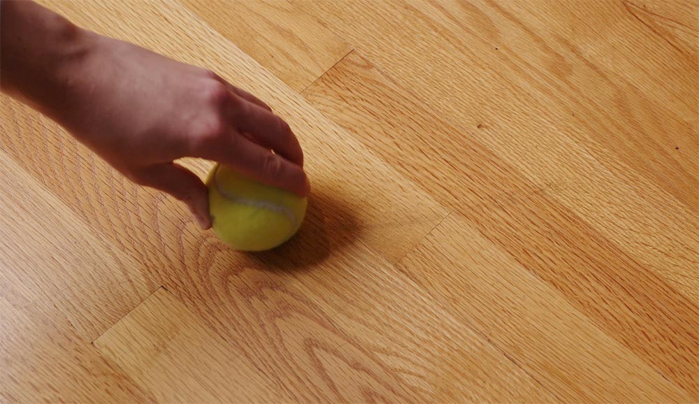 A tennis ball dabbed with a water and vinegar mix, used to gently rub a spot out of a hardwood floor