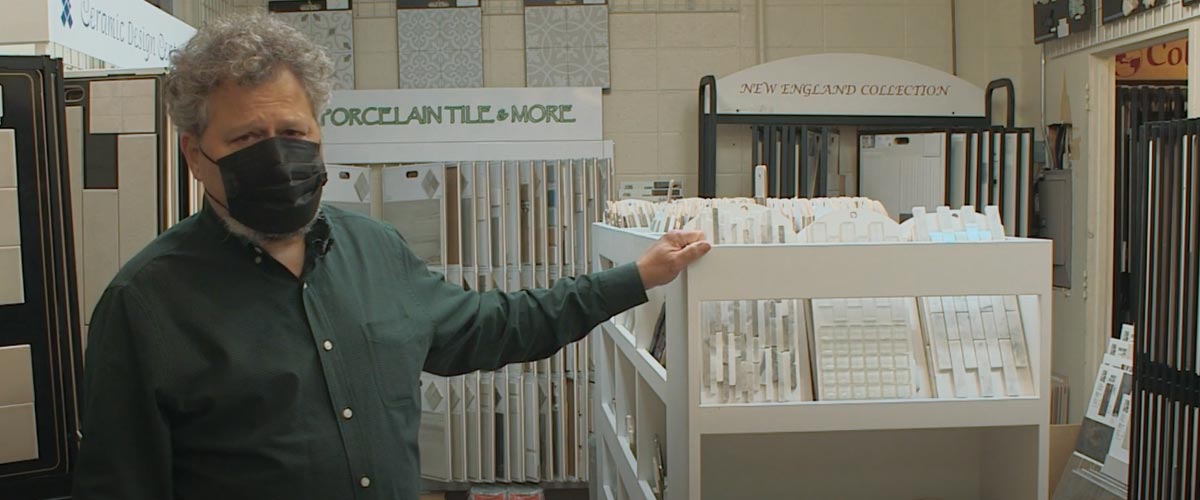 Ken Fain stands next to Island Carpet mosaic tile collection in tile room